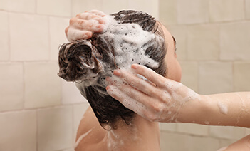 Frau arbeitet Shampoo in die Haare ein. Kategoriebild Shampoo / Haarpflege
